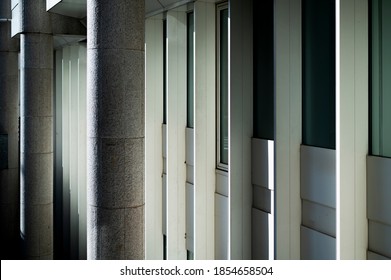 Facade Of 1980s Office Building With Graded High Contrast Shadowing Cast Over The Exterior Concrete Columns Sunny Day