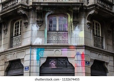 Facade of aged polluted building with red, green, yellow, purple and pink spots.