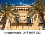 Facade between palm trees of the Elche Town Hall in Elche, Alicante, Valencian Community, Spain, in daylight