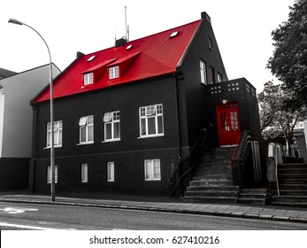 Facade of a black house with a vibrant red roof and doors in the old town of Reykjavík, Iceland. Exterior view of a Nordic downtown neighborhood building. Traditional Icelandic architecture.