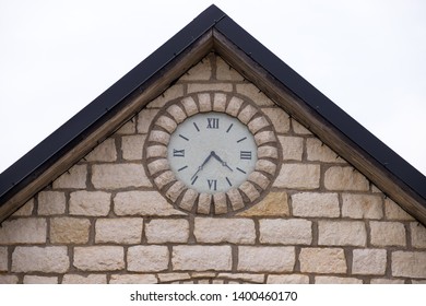 The facade of the brick building with a clock. Attic room with a slanting roof