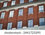 Facade of a brick building with symmetrical windows reflecting the sky, architectural background in Leeds, UK.