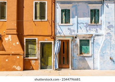 Facade of bright blue and orange painted houses with rustic green shutters and derelict paint.
