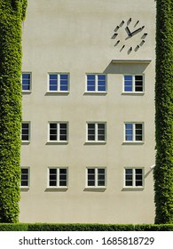 Facade of the building with a clock and columns covered with ivy