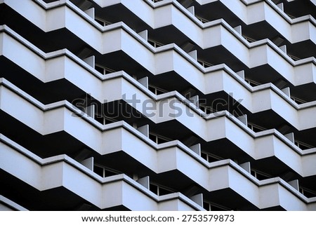 The facade of the building has a repeating pattern of white and dark rectangles, creating a zigzag pattern.