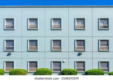Facade of a building with light blue interior and square single hung windows