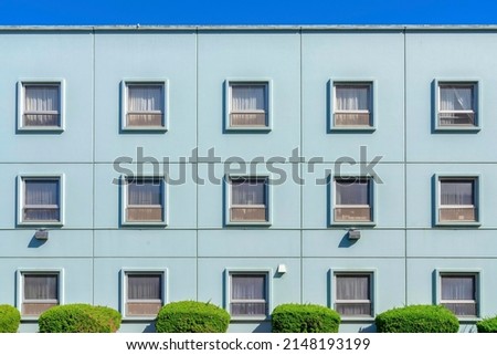 Facade of a building with light blue interior and square single hung windows