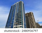 Facade building on blue sky background. Modern buildings exterior with glass windows, balconies. Buildings architecture. Skyline Skyscrapers. Tower crane on Construction of the Residential building. 
