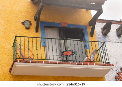 Facade Of A Colonial House. Open Balcony On An Old Building With A Yellow Wall. The Exterior Of The Old House, Handmade Furniture On The Balcony.