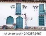 facade of colonial house with white walls and blue doors and windows, with flowers and vines