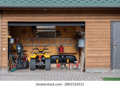 Facade front view open door ATV quad bike motorcycle parking messy garage building with wooden siding at home driveway backyard and lawn path. House warehouse for tools and equipment . Garage sale