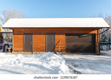 Facade Front Wall View Closed Door ATV Home Garage Workshop Clutter Shed Storage Warehouse Building Snowy Winter Day. House Organized Warehouse Tools Equipment. Snow Clean Removal Cold Sunny Weather