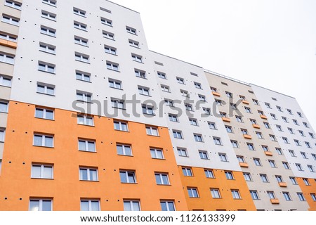 Facade of gray-orange building with windows. 