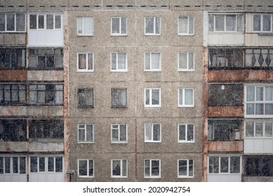 Facade Of A Grey Multi-storey Soviet Panel Building In The Fallen Snow. Russian Old Urban Residential Houses With Windows. Typical Russian Neighborhood.