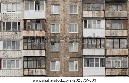 Facade of a grey multi-storey soviet panel building in the fallen snow. Russian old urban residential houses with windows. Typical russian neighborhood.