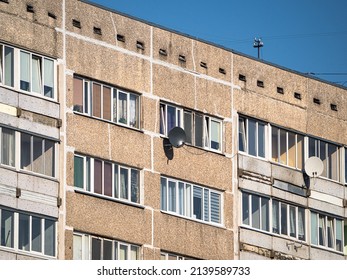 Facade of high storey, residential, soviet block of flats panel house with two TV satellite dishes.