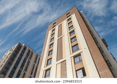 Facade of a high-rise multi-storey residential building, decorated with modern materials against the sky. Modern high-rise residential building against the sky. Low angle view of the building. - Powered by Shutterstock
