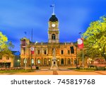 Facade of historic Town hall building in regional centre in Victoria state - Ballarat. Brightly illuminated at sunrise with Queen Victoria statue in foreground.