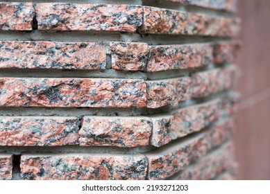 The facade of the house is decorated with decorative facade red stone, close up, selective focus. Facade decorative stone