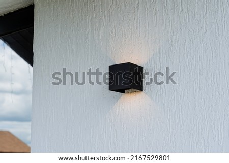 Facade lighting of the house, white wall with black lamp, square lamp shape, street lighting, beautiful exterior design. High quality photo