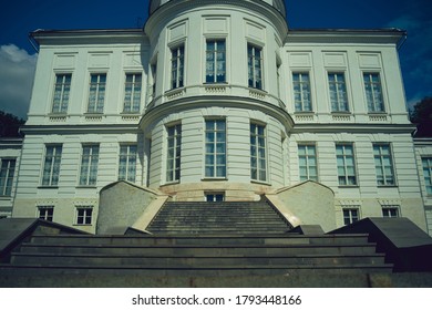 Facade of luxury estate with stairs. From below exterior of luxury mansion with staircase and many windows on sunny summer day