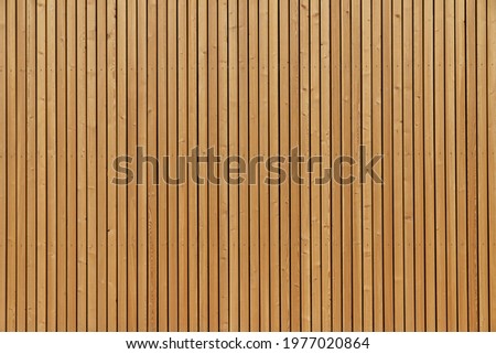 Facade made of wooden vertical planks. Warm yellow color. Close up.