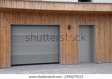 facade of modern wooden house with terrace and closed pvc rolling shutters of new suburban home