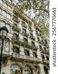 Facade of a modernist building in Barcelona, Spain featuring wrought iron balconies, intricate ornaments, and arched windows.