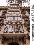 Facade of a modernist building in Barcelona, Spain featuring wrought iron balconies, intricate ornaments, and arched windows.