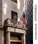 The facade of the New York Stock Exchange with the American flag illuminated by sunlight