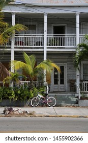 The Facade Of An Old Building On Key West With A Parked Bike And Palm Trees.