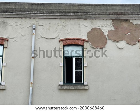 Facade of old building with window and drain pipe with serious water infiltration leading to paint peeling off example of bad maintenance