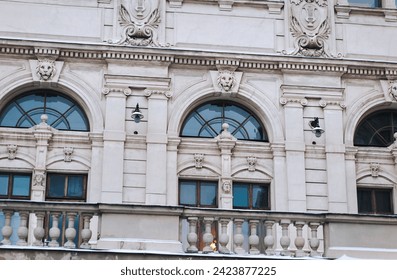 Facade of the old classical building of the Opera and Ballet Theater in Lviv, Ukraine. Pilasters, capitals, stucco and a window with a mascaron. Relief and decorative elements of architecture.