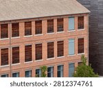 Facade of an old red brick textile factory in Mulhouse with rows of windows boarded up with wood, industrial heritage in Alsace, France