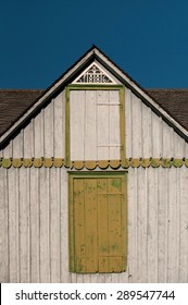 The facade of the old shabby house with window and wooden doors in green and grey.