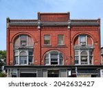 Facade of ornate brick main street commercial building built in the 1800s, with stores on the ground floor and apartments above