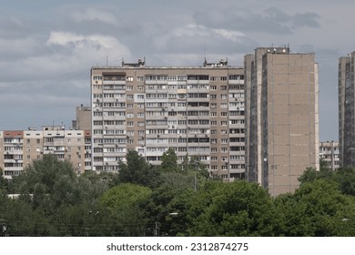 Facade of an overcrowded shabby apartment buildings of a multi-storey Soviet panel house, on a hot summer day.