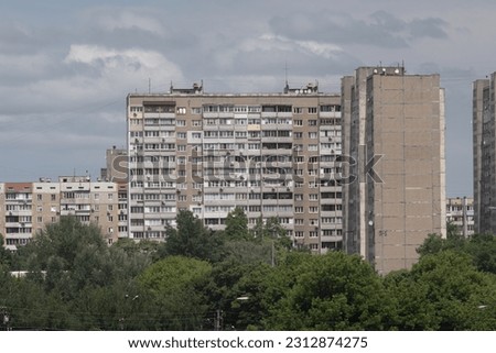Facade of an overcrowded shabby apartment buildings of a multi-storey Soviet panel house, on a hot summer day.