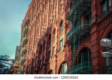 Facade Of The Puck Building In Little Italy, New York City. Detailed View Of The Windows And Contrast Of Colours Between The Red Bricks Of The Facade And The Fire Exit Stairs In Green Iron