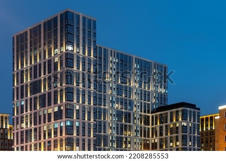 The facade of a residential building in the evening with street lighting . Modern architecture . Night City. 