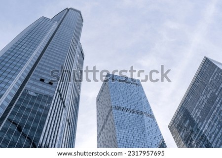 The facade of several office and residential high-rise towers of different geometric shapes made of glass in the business center of the city . Futuristic architecture .