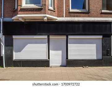 Facade Of A Store With Door And Shop Windows Closed With White Roll Down Shutters