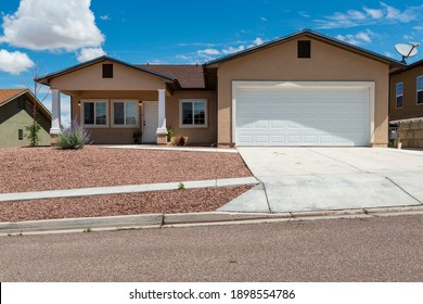 The facade of a suburban house with garage and driveway, in a suburb in the outskirts of the city of Gallup, New Mexico, USA