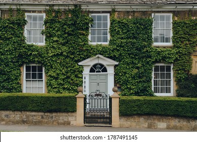 Facade of a traditional house in Broadway, Cotswolds, UK, covered with ivy.