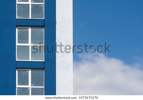 Facade of an\
unfinished apartment building. The wall of the apartment and the\
blue sky divide the frame in\
half.
