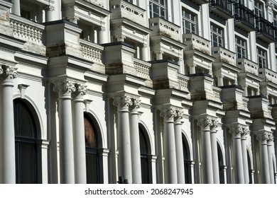 Facade of a white building with many white windows. House facade of old historical building with white walls. Exterior design of apartment building with ornamental details. High quality photo