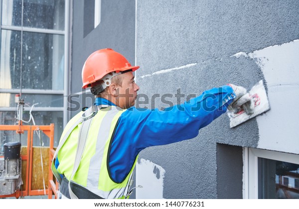 Facade worker\
plastering external wall of\
building