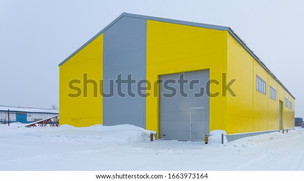 Facade of a yellow metal warehouse, a commercial\
building with entrances for cars for storing goods. The concept of\
storage of goods by importers, exporters, wholesalers, transport\
enterprises, custom