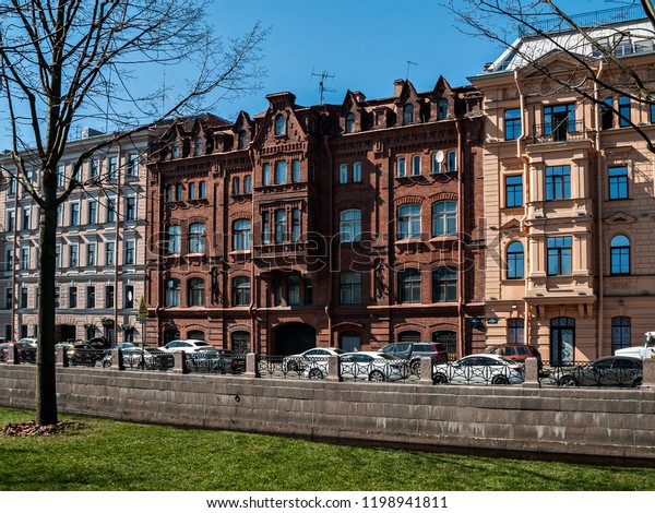 The facades of multi-storey old houses on the street\
with heavy traffic and cars in the city of St. Petersburg in early\
spring on a sunny day