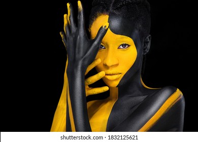 Face Art. Woman With Black And Yellow Body Paint. Young African Girl With Colorful Bodypaint. An Amazing Model With Yellow Makeup. Closeup Face.